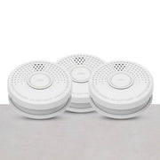 Three white smoke detectors with a circular design and a central button, placed against a grey background.
