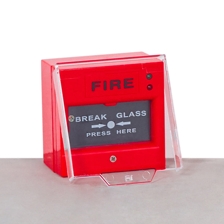 Red manual call point fire alarm with protective glass and activation button, mounted on a surface